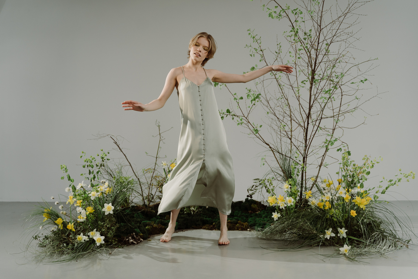 A Woman in Beige Dress Dancing beside the Plants
